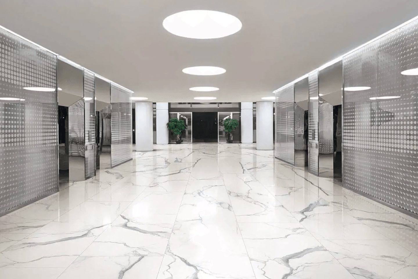 A large white lobby with two elevators and a skylight.