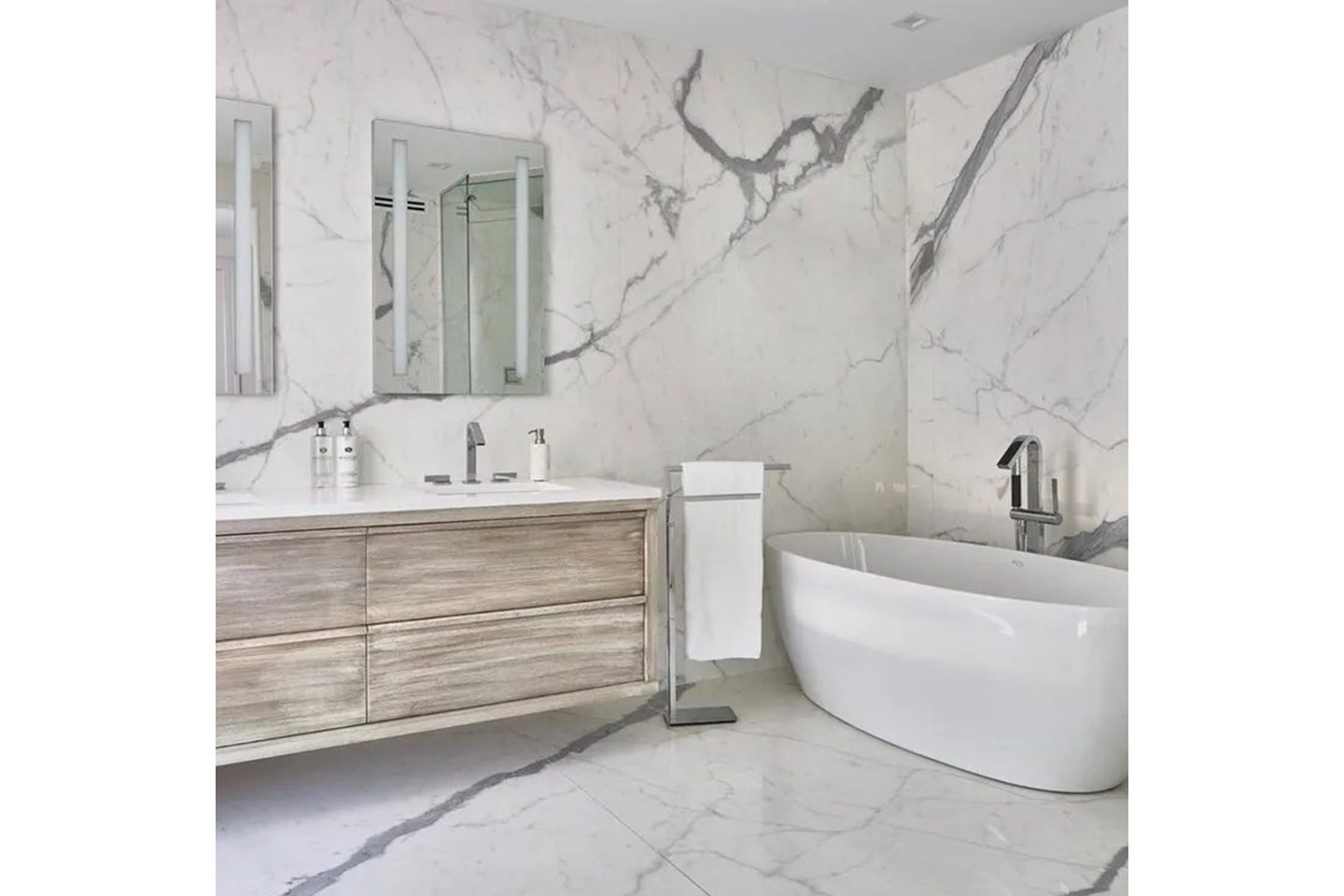 A bathroom with marble walls and floors, and a large tub.